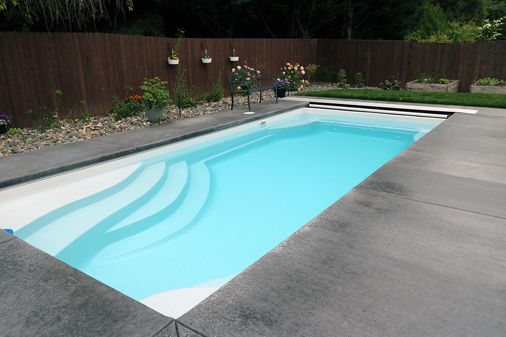 a fiberglass pool from Water's Edge Pools & Spas in a home backyard
